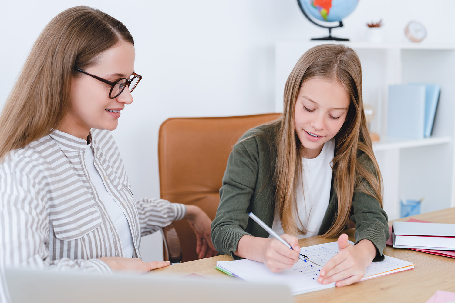 Homeschool education. Tutoring and domestic education concept. Caucasian teacher tutor mother helping explaining new topic homework to her daughter student schoolgirl at home classroom.